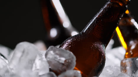 Primer-Plano-De-Una-Persona-Tomando-Una-Botella-De-Vidrio-Fría-De-Cerveza-Fría-O-Refrescos-De-Un-Cubo-Lleno-De-Hielo-Sobre-Fondo-Negro-1